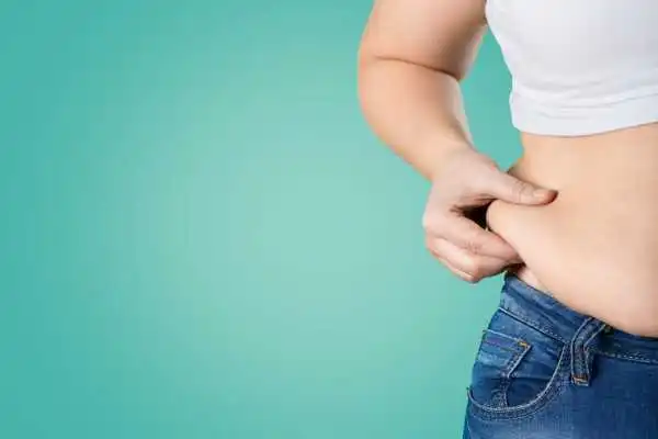 Image of woman pinching her love handles to show weight gain Wooburn Green