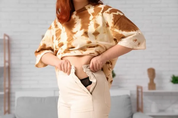 Image of woman trying to do her trousers up after pregnancy weight gain Wooburn Green
