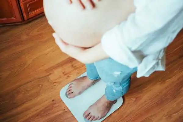 Image of woman weighing herself and experiencing weight gain through pregnancy Wooburn Green